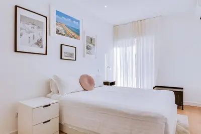 a white bedroom with a white bed and a window at Apartment with Rooftop and work space in Quarteira in Quarteira