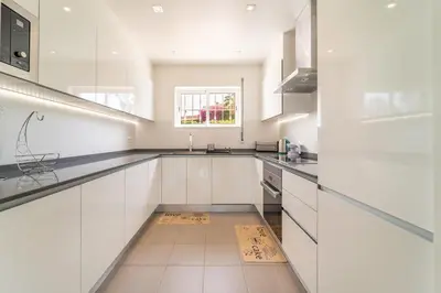 a white kitchen with white cabinets and a window at Villa Vilamoura NATURE GREEN GOLF AND POOL in Quarteira