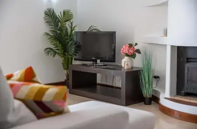 a living room with a white chair and a television at Brisa Mar-Aveiros Apatment by Dalma Portuguesa in Albufeira