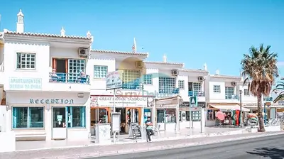 a building on a street in a city with a palm tree at Sereia da Oura by Sunny Deluxe in Vale de Pedras