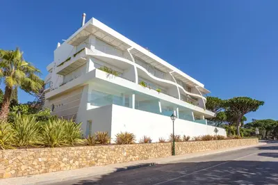 a large white building with palm trees in front of it at Apartment Atlantic - Vale de Lobo in Almancil