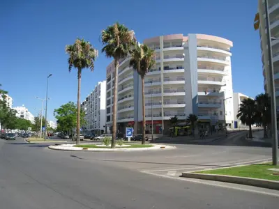 an empty street with palm trees in front of a building at Appartement Quarteira in Quarteira