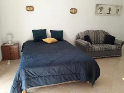 a bed with a blue comforter and a chair in a bedroom at Quarteira Azul in Quarteira