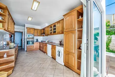 a kitchen with wooden cabinets and a washer and dryer at Atlantic Sul in Albufeira