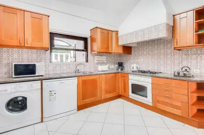a kitchen with wooden cabinets and a washer and dryer at Casa Sol in Albufeira