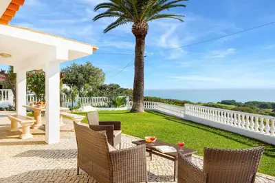 a patio with a table and chairs and a palm tree at Casa Sol in Albufeira