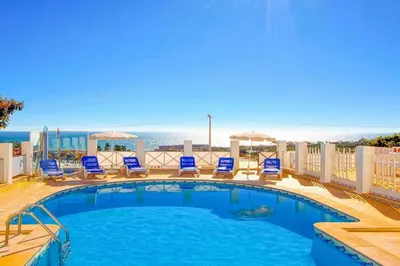 a swimming pool with chairs and a view of the ocean at Villa Mar in Albufeira