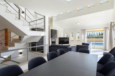 a dining room with a table and chairs and a staircase at Stunning Villa with Heated Pool, Garden, BBQ in Quarteira