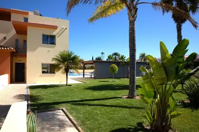 a yard with palm trees and a house at Stunning Villa with Heated Pool, Garden, BBQ in Quarteira