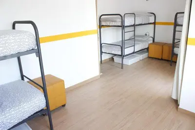 a room with three bunk beds and a wooden floor at Rich & Poor Hostel Albufeira in Albufeira