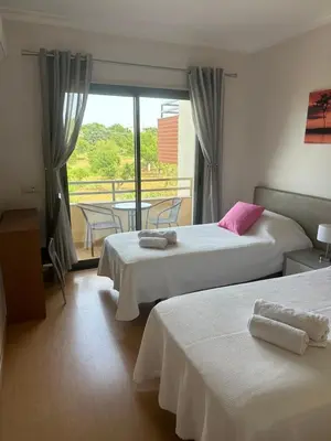 a hotel room with two beds and a balcony at Jardins da guia in Albufeira
