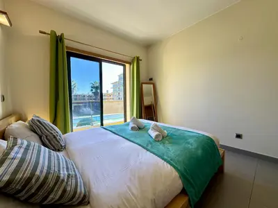 a bedroom with a bed with a large window at Quarteira Stylish 3 with Pool by Homing in Quarteira
