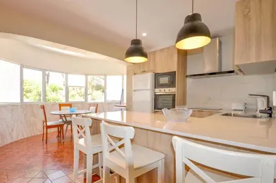 a kitchen with white chairs and a counter top at Villa Atlantico in Quarteira