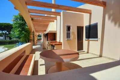 a patio with a wooden table and a bench on a house at Villa Gardenia in Quarteira