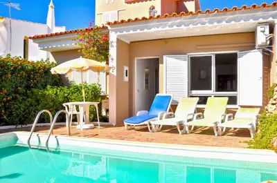 a pool with chairs and an umbrella next to a house at Vista Golfe in Quarteira