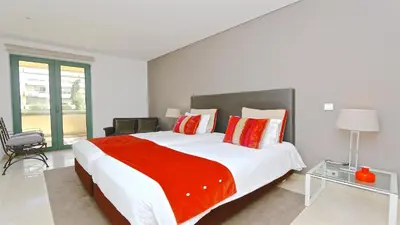 a white bedroom with a large bed with red pillows at Aquamar 15 - Clever Details in Vilamoura