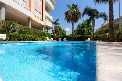 a swimming pool in front of a building with palm trees at Antelius 82 - Clever Details in Vilamoura