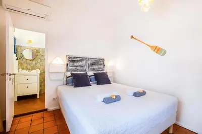 a bedroom with a white bed with blue pillows at Casa do Cacto in Olhos de Água