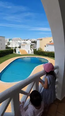 two children standing on a balcony looking at a pool at Alta Oura in Albufeira
