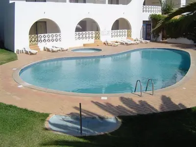 a large swimming pool with chairs and a building at Alta Oura in Albufeira