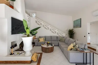 a living room with a gray couch and a tv at Quinta do Lago, Charme e Luxo no Centro da Quinta do Lago, 5 Quartos in Quinta do Lago