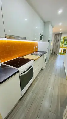 a large kitchen with a stove and a sink at Apartamento a 5 min a pé da praia, com terraço grande ao sol, no Rés-Chão in Quarteira