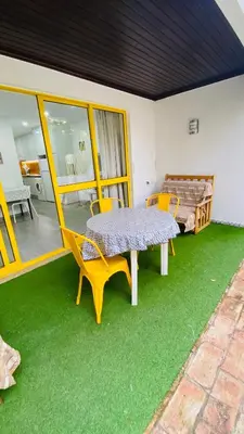 a patio with a table and chairs on the grass at Apartamento a 5 min a pé da praia, com terraço grande ao sol, no Rés-Chão in Quarteira