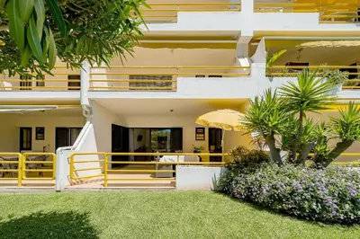 a building with a balcony with an umbrella and flowers at Apartamento a 5 min a pé da praia, com terraço grande ao sol, no Rés-Chão in Quarteira