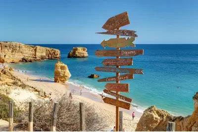 a street sign on a beach with a bunch of signs at Apartamento Perfect Holidays in Albufeira