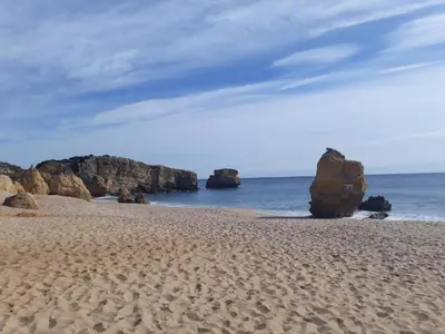 a sandy beach with some rocks in the ocean at Apartamento Perfect Holidays in Albufeira