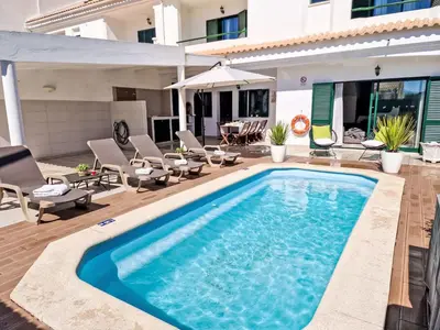a pool with chairs and an umbrella next to a house at Holiday Home V2 Caliços - VIP Properties by Interhome in Albufeira
