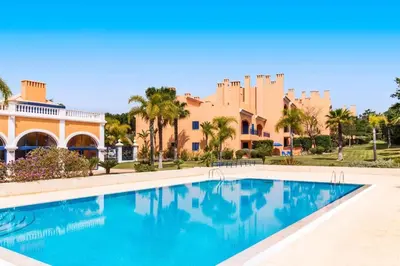 a swimming pool in front of a building with a castle at 2 bedroom Vila Sol Golf Resort in Quarteira