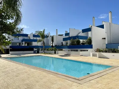 a villa with a swimming pool in front of a building at Quarteira Deluxe With Pool by Homing in Quarteira