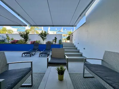 a patio with benches and chairs and a staircase at Quarteira Deluxe With Pool by Homing in Quarteira