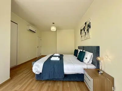 a bedroom with a large bed and a wooden floor at Quarteira Deluxe With Pool by Homing in Quarteira