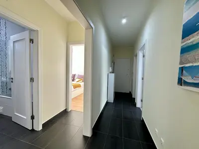 a hallway with white walls and black tile floors at Quarteira Deluxe With Pool by Homing in Quarteira