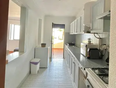 a kitchen with white cabinets and a refrigerator at Casa Caki - A 15 minutos da praia in Albufeira