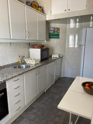 a kitchen with white cabinets and a sink and a refrigerator at Villa Snoppy in Albufeira