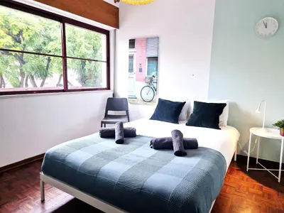 a bedroom with a bed with a chair and a window at Casa da Baixa in Faro