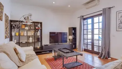 a living room with a white couch and a tv at Villa Frederique in Albufeira