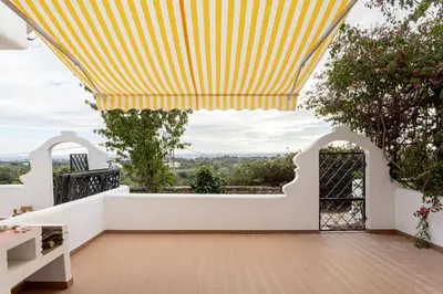 a balcony with a yellow and white striped awning at Estúdio 24 em Santa Bárbara de Nexe - Faro in Colmeal