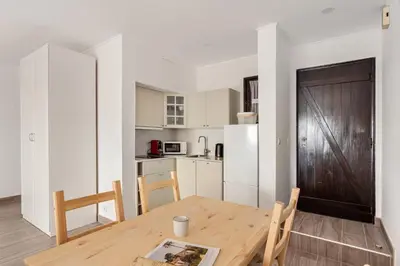 a kitchen and dining room with a wooden table at Estúdio 24 em Santa Bárbara de Nexe - Faro in Colmeal
