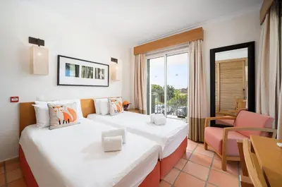 a hotel room with two beds and a balcony at 3 bedroom Vila Sol Golf Resort- 1st Floor in Quarteira