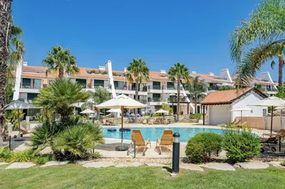 a resort with a swimming pool with chairs and umbrellas at 3 bedroom Vila Sol Golf Resort- 1st Floor in Quarteira
