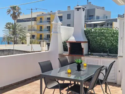 a table and chairs on a balcony with a fireplace at Vivenda das Conchas - Just 50 Meters from the Beach in Quarteira