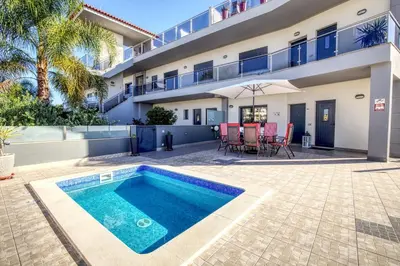 a swimming pool in front of a house at Modern Vacation Home With Pool In Quarteira in Quarteira