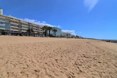 a sandy beach with palm trees and a building at Modern Vacation Home With Pool In Quarteira in Quarteira