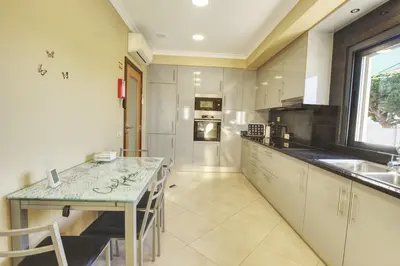 a large kitchen with a table and a sink at Modern Vacation Home With Pool In Quarteira in Quarteira