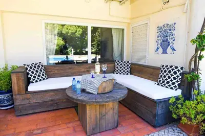 a patio with two benches and a table and a window at Vale do Lobo 5 Bed Villa with Large Pool overlooking Golf Course in Almancil