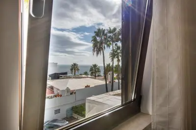 a window with a view of palm trees and the ocean at Albufeira View Sea Apartment Luxury in Albufeira